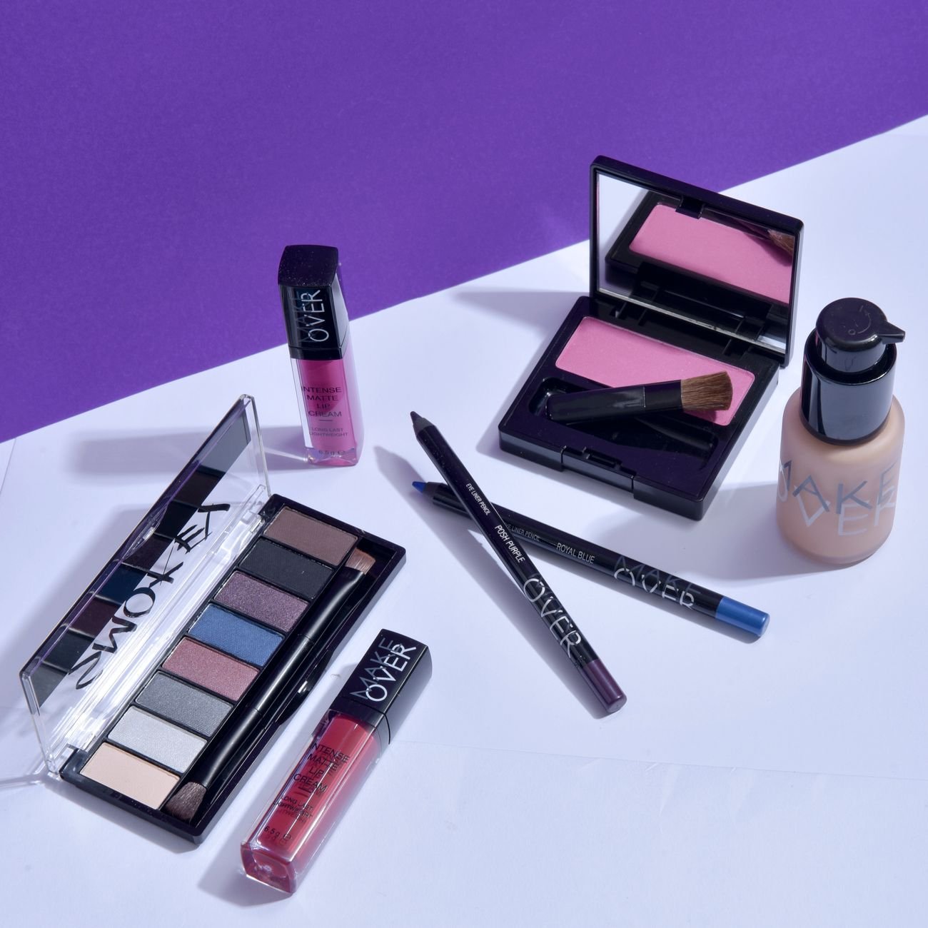 Flat lay of various makeup products on a stylish purple background